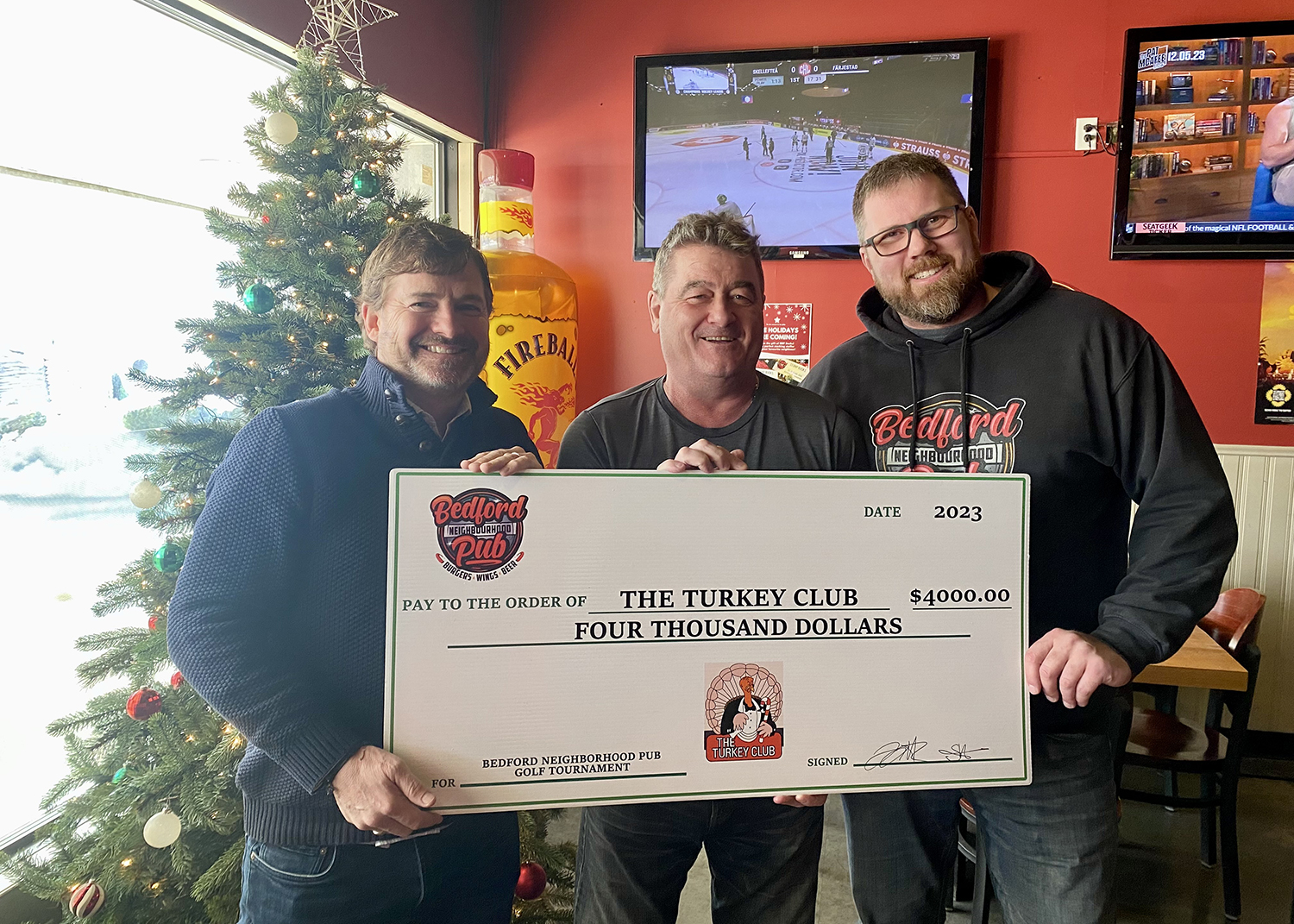 Bedford Neighbourhood Pub owners Troy Harnish and Scott MacDonald present a cheque to the Turkey Club's Rick Thomas in 2023.